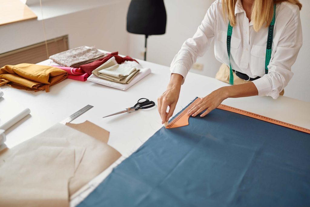 dressmaker-measures-cloth-at-workplace-in-workshop-QTCK3JH.jpg