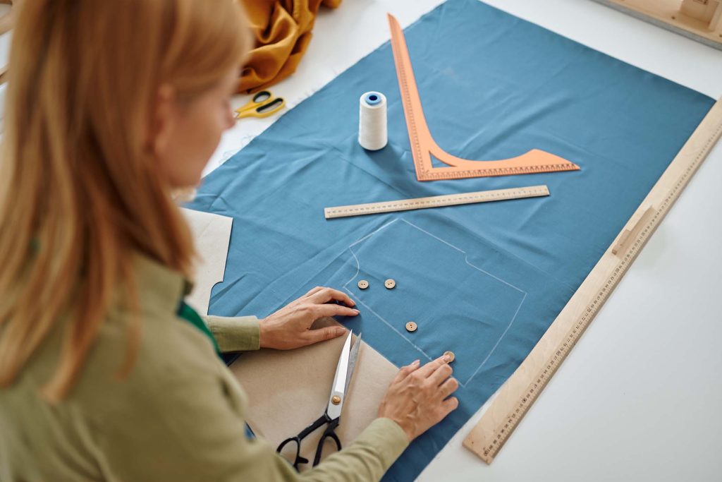 dressmaker-measures-cloth-on-the-table-in-workshop-3E4AR78.jpg