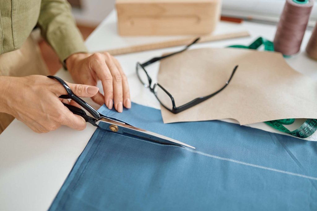 dressmaker-with-scissors-cuts-cloth-in-workshop-VFV8UXT.jpg